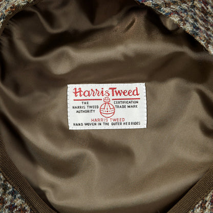 A brown tweed jacket with a Beige Houndstooth Harris Tweed Ivy Contemporary Cap by Wigéns label on it.
