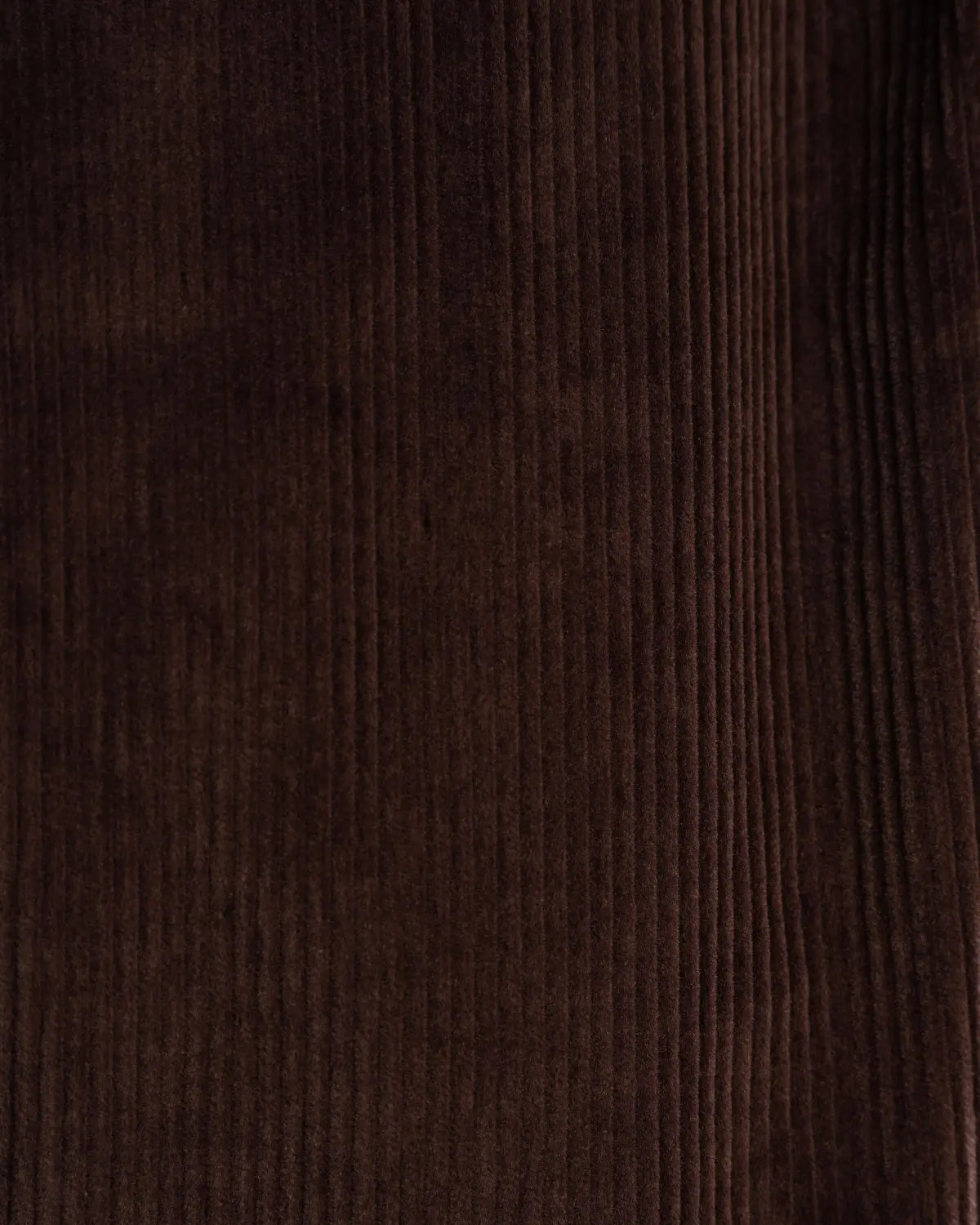 A close-up view of the dark brown fabric of Cavour Brown Wide Leg Pleated Corduroy Trousers, featuring vertical, raised ridges with deep shadows between the velvet-like lines. , available at Richard Gelding Mayfair