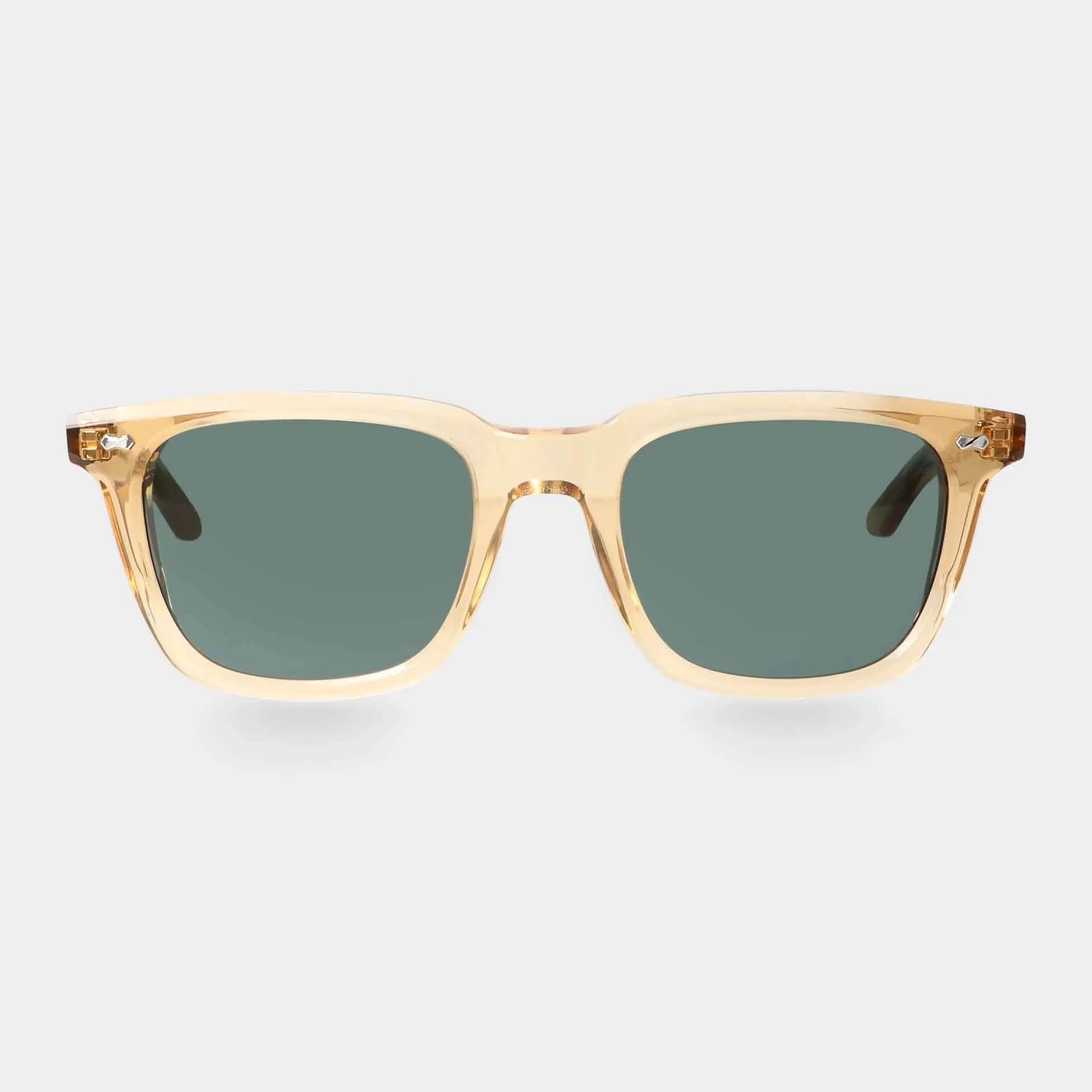 The Carré Eco Champagne by TBD Eyewear features translucent, light beige frames with a slightly glossy finish and rectangular bottle green lenses. The clear arms are visible, set against a plain light gray background. , available at Richard Gelding Mayfair