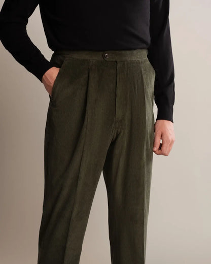 Cavour Green Wide Leg Pleated Corduroy Trousers in olive green, featuring a high-waisted wide-leg cut with front pleats, button closure, and side pockets, worn with a black long-sleeved shirt tucked into the waistband. , available at Richard Gelding Mayfair