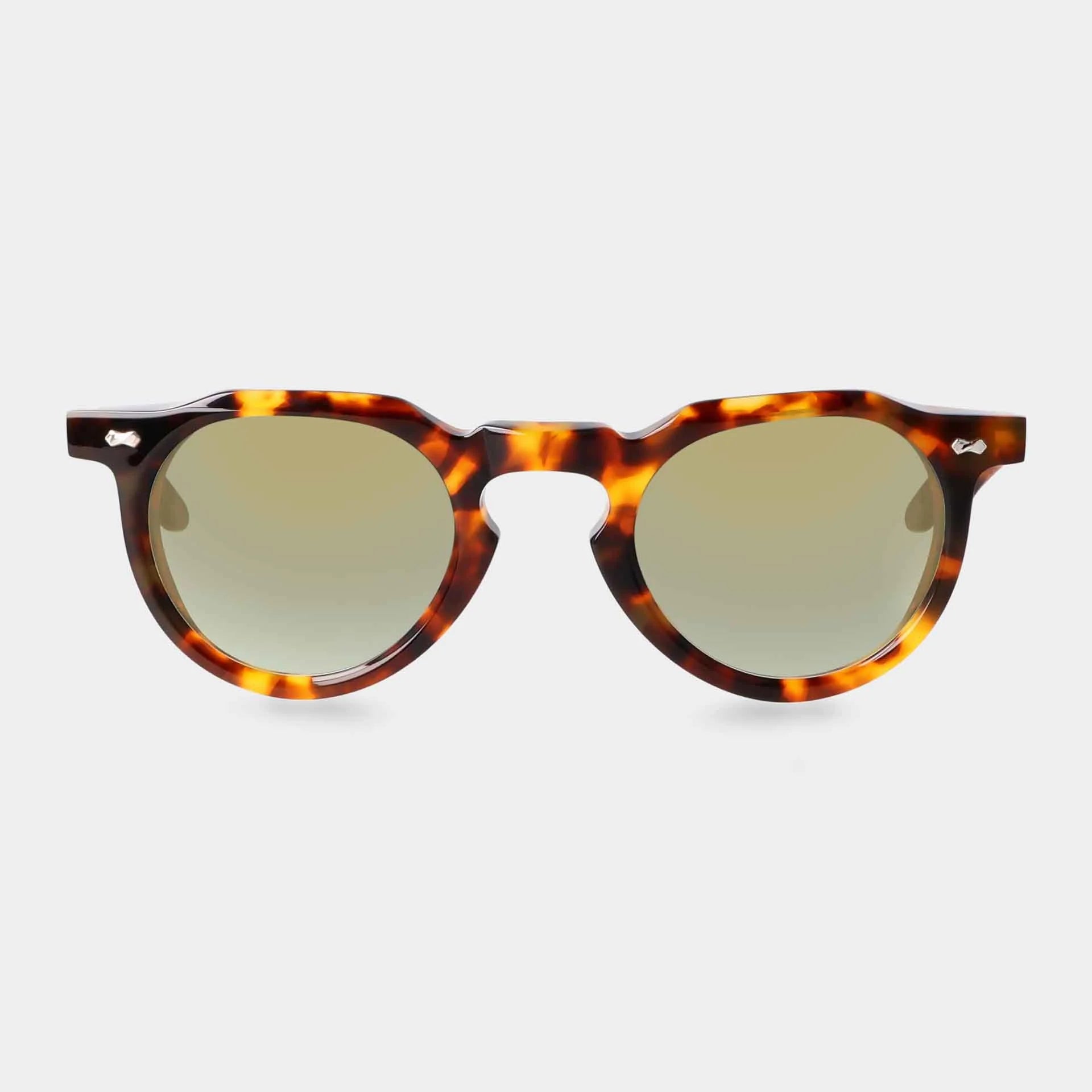 TBD Eyewear’s Hem Eco Spotted Havana sunglasses feature round tortoiseshell-patterned frames with a glossy finish, small silver hinge accents, and mirror green lenses, shown against a plain white background. , available at Richard Gelding Mayfair