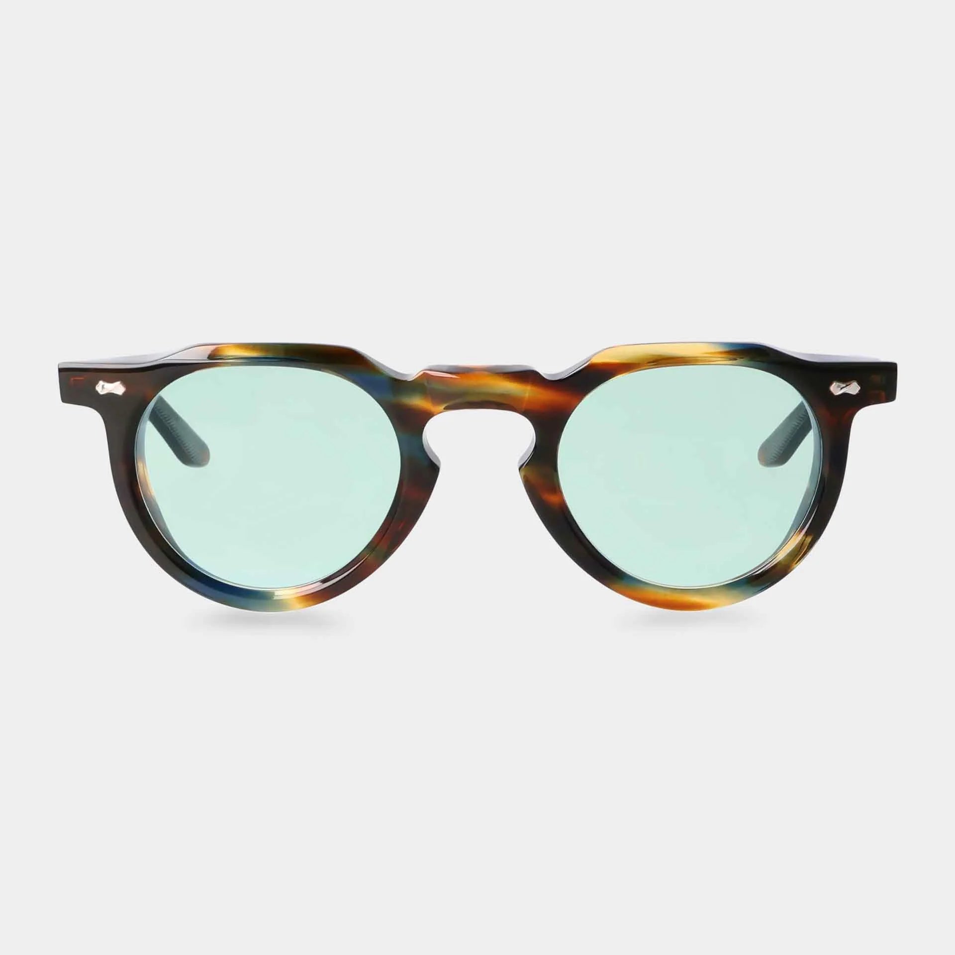 The Hem River | Light Green sunglasses by TBD Eyewear feature thick, round tortoiseshell-patterned frames, green-tinted lenses, a keyhole bridge, and small silver accents by the hinges. Shown on a plain white background. , available at Richard Gelding Mayfair