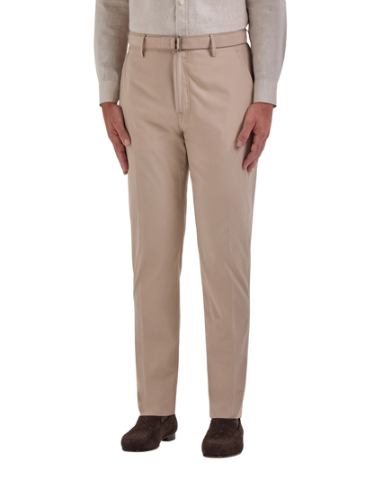 A person wears Canali Beige Cotton Poplin Self-Belt Trousers, neatly pressed and slim-fit, with a tucked-in light long-sleeve shirt and dark brown shoes. Only the lower body is shown against a white background. , available at Richard Gelding Mayfair