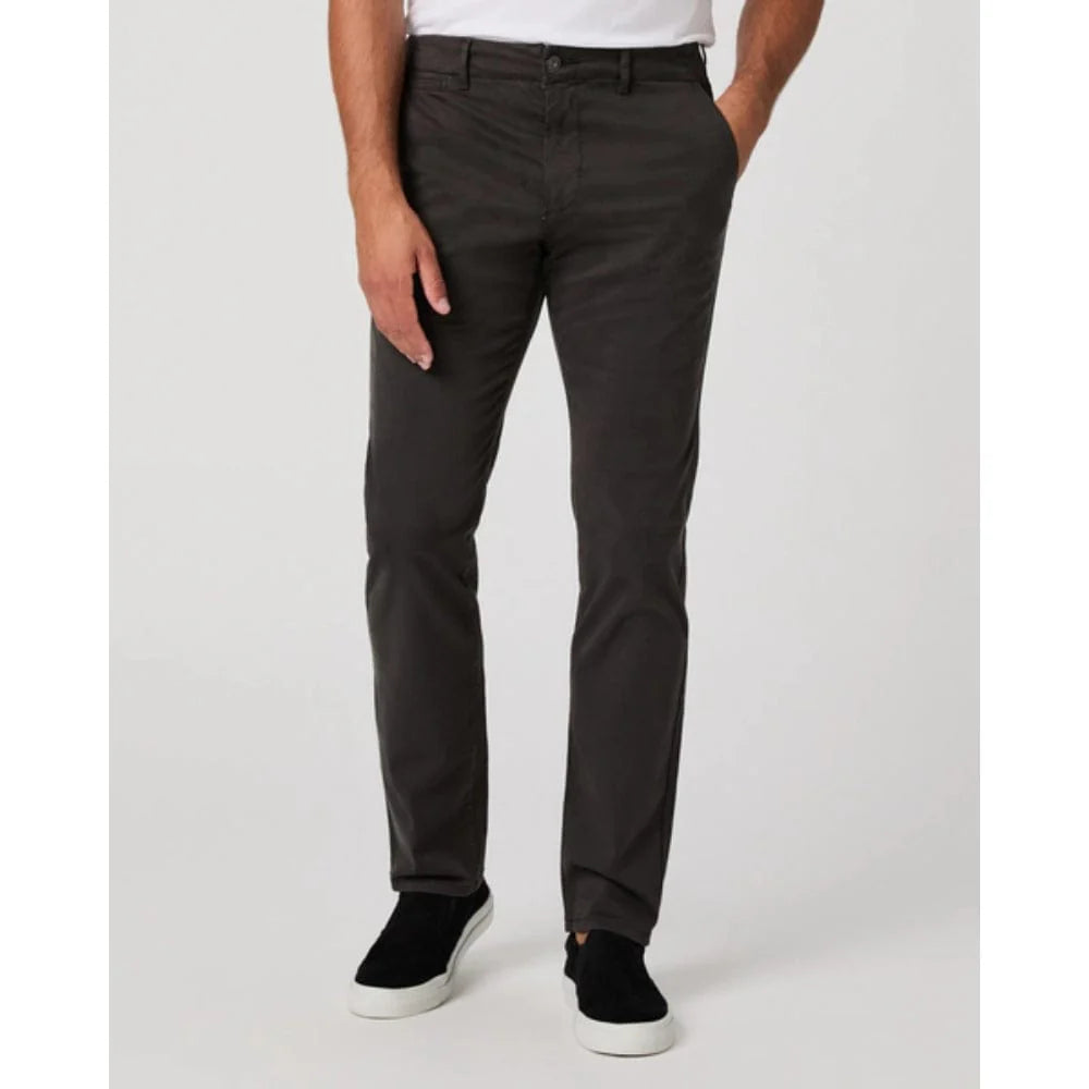 Wearing Paige’s Dark Iron Grey Danford Cotton Chino, a person stands against a plain light background. The straight-fit pants are paired with a tucked white shirt and black slip-on shoes; only the lower torso and legs are shown. , available at Richard Gelding Mayfair