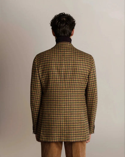 A rear view of a person wearing a Cavour Brown Shepherds Check Tweed Blazer over a dark turtleneck sweater, paired with light brown corduroy trousers against a plain, light-colored background. , available at Richard Gelding Mayfair